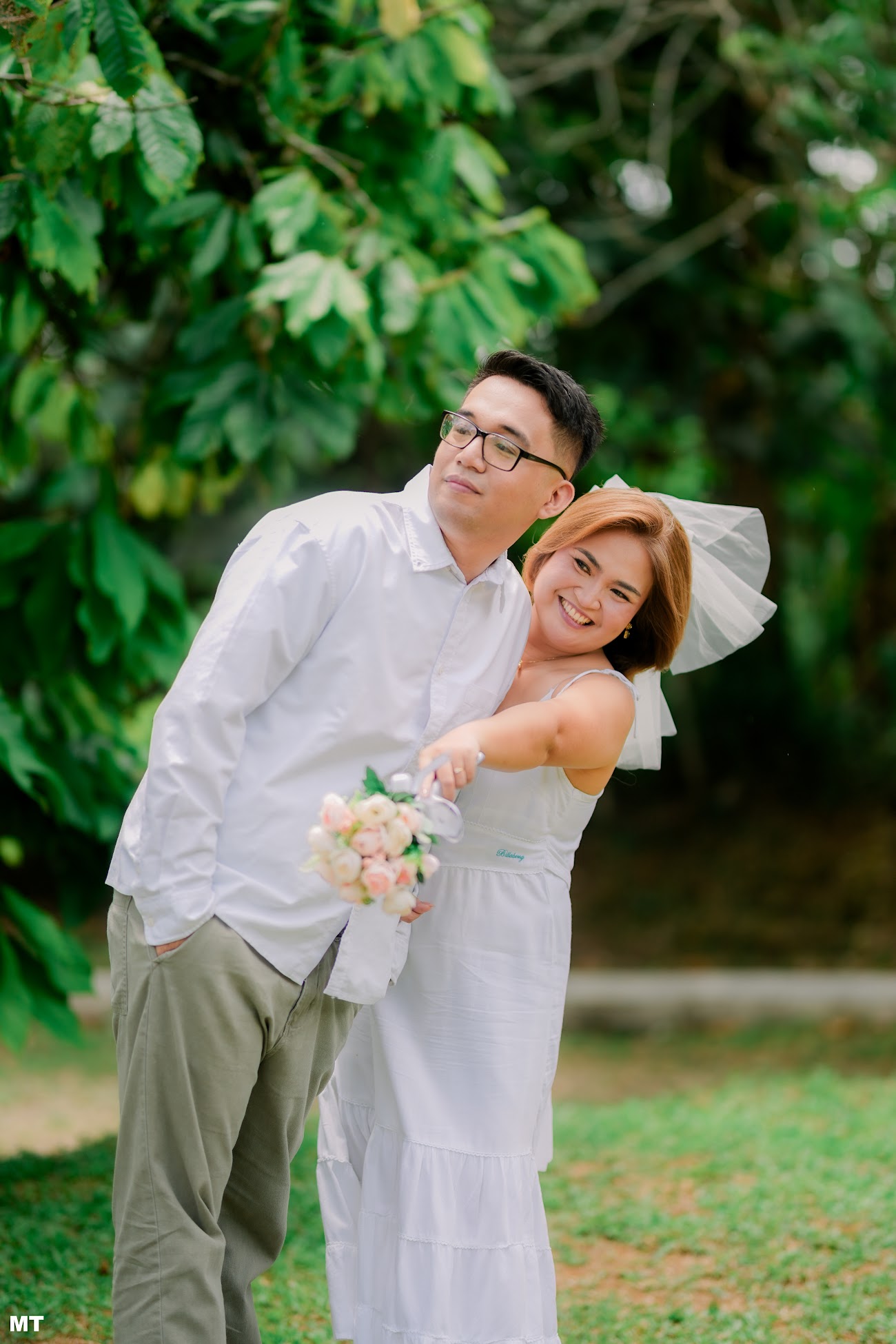 Laddie hugging Paulo from the side and pointing ahead, holding her bouquet