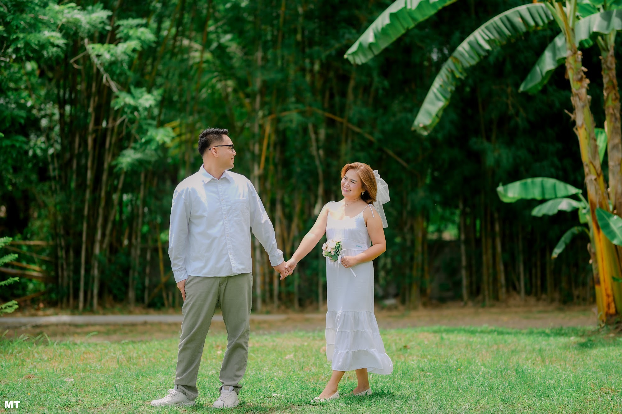 Paulo and Laddie holding hands in front of a bamboo grove