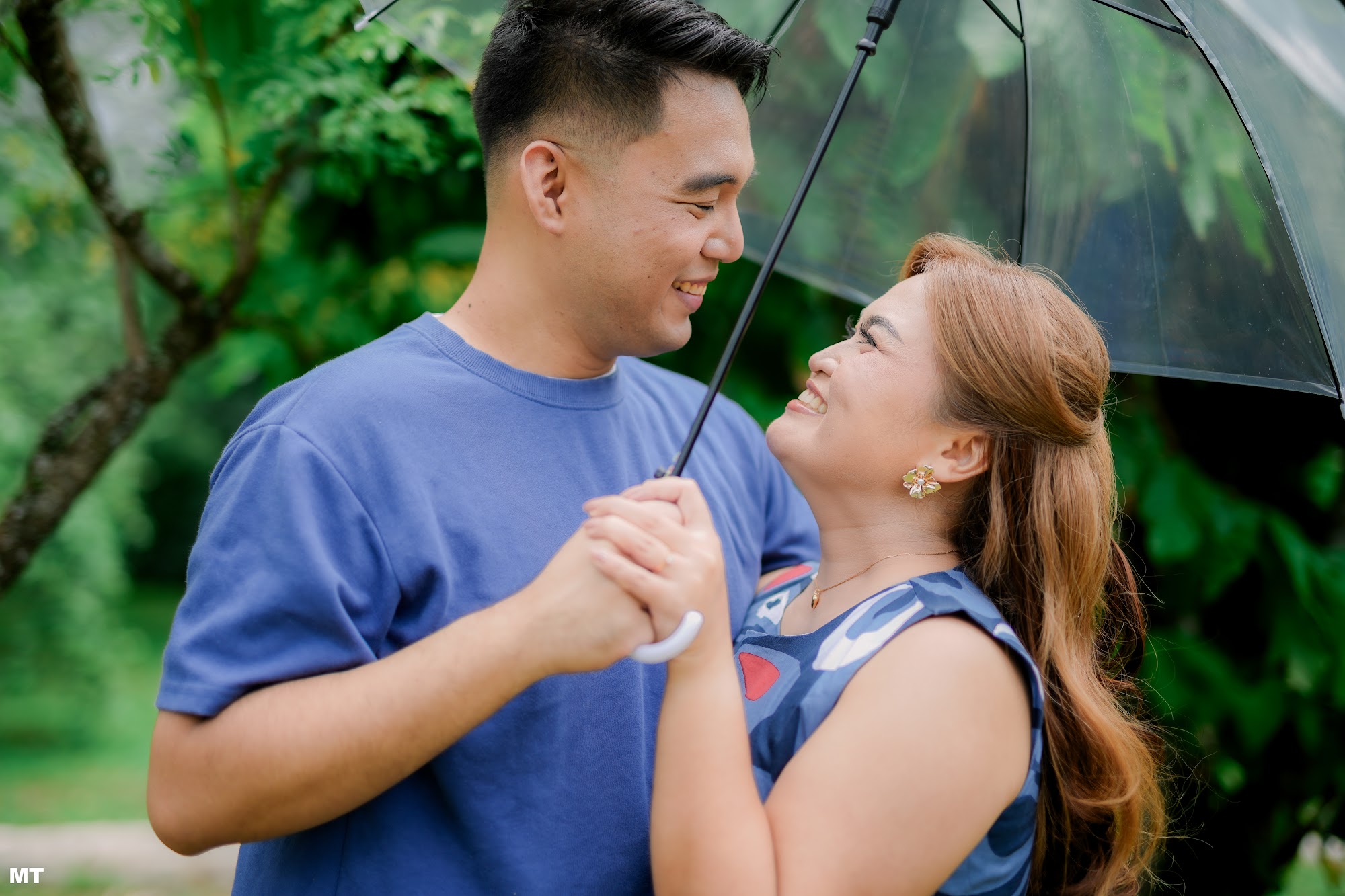 Paulo and Laddie laughing under a clear umbrella