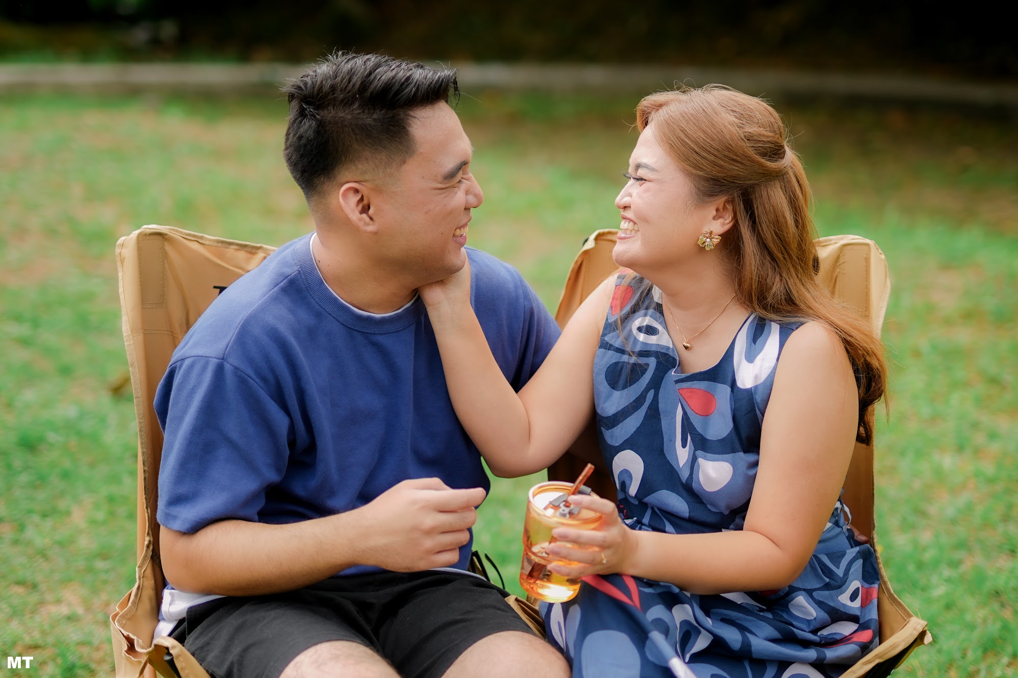 Paulo and Laddie smiling at each other, seated outdoors on a lawn